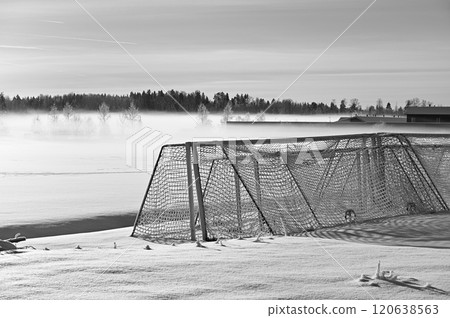 black-and-white photograph captures a serene winter landscape with a frosted soccer goal on a snow-covered field 120638563