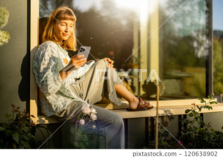 Relaxing with Phone in Sunlit Garden 120638902