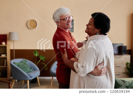 Portrait of Caucasian senior man and Black woman slow dancing together in cozy living room enjoying music copy space Portrait of Caucasian senior man and Black woman slow dancing together in cozy living room enjoying music copy space 120639194