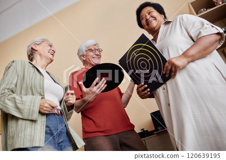 Low angle view at group of senior friends smiling happily and holding vinyl records while enjoying music together Low angle view at group of senior friends smiling happily and holding vinyl records while enjoying music together 120639195