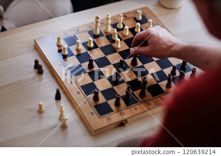 Top view close up of unrecognizable man playing chess with focus on hand moving pawn piece copy space Top view close up of unrecognizable man playing chess with focus on hand moving pawn piece copy space 120639214