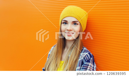 Portrait of modern young teenage blonde girl smiles in yellow hat on orange background 120639395