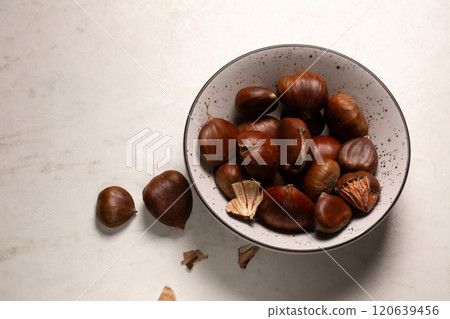 Delicious edible chestnuts in a small bowl on a white table 120639456