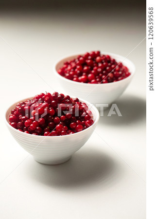 Two bowls of red lingonberries on white background Two bowls of red lingonberries on white background 120639568