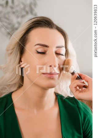 A stylist makes a makeup, applies blush with a brush 120639813