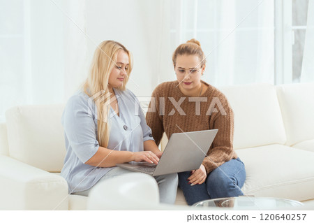 Two women on a couch looking at a laptop Two women on a couch looking at a laptop 120640257