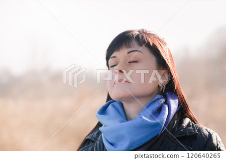 A woman has closed her eyes and is inhaling air and is in a calm and relaxed state A woman has closed her eyes and is inhaling air and is in a calm and relaxed state 120640265