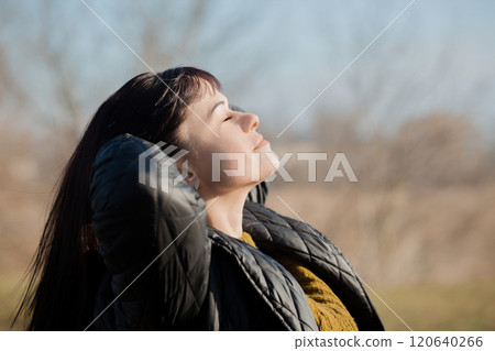 A woman is wearing a black jacket and a knitted sweater 120640266