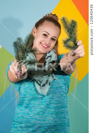 A woman holds two Christmas tree branches in her hands and smiles 120640436