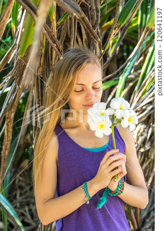 Woman holding a white flower of Plumeria in her hand 120641197