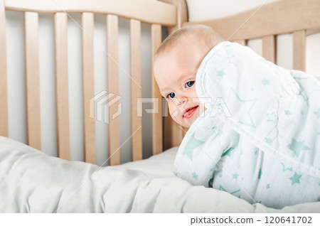 Curious Baby Standing in a Wooden Crib 120641702