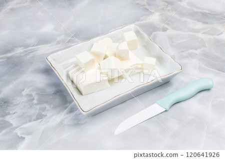 Sliced feta - white cheese in the saucer. Top view. 120641926