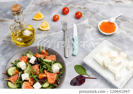 Salad with salmon, white cheese and vegetables on the plate with ingredients. 120641947