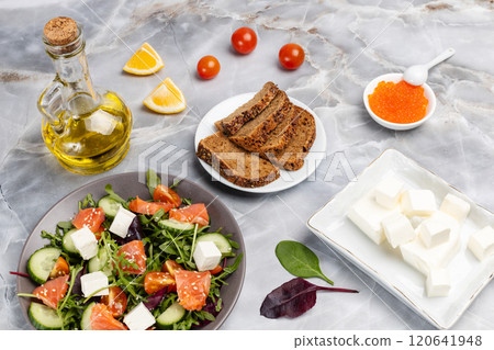 Salad with salmon, white cheese and vegetables on the plate with ingredients. 120641948
