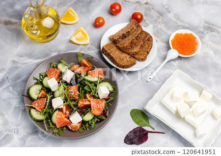 Salad with salmon, white cheese and vegetables on the plate with ingredients. 120641951
