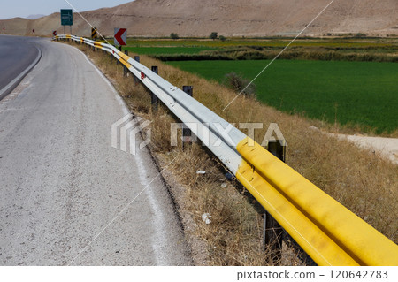 Roadside view with guardrails along a highway near green fields and mountains Roadside view with guardrails along a highway near green fields and mountains 120642783