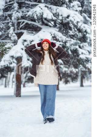 Young woman laughs and throws snow in a winter snowy park. Holidays, rest, travel concept. Young woman laughs and throws snow in a winter snowy park. Holidays, rest, travel concept. 120642848