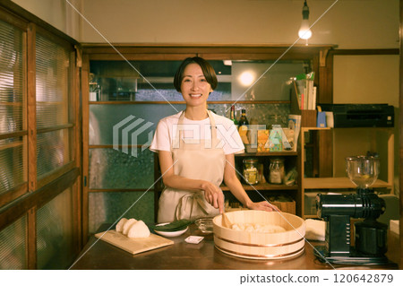 在老民居的廚房裡，一位中年婦女正在綁飯糰。 120642879