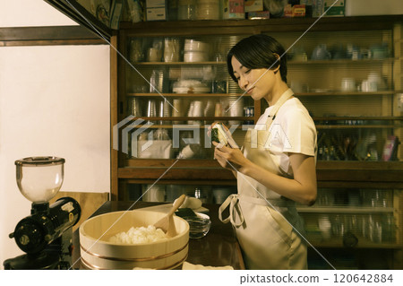 在老民居的廚房裡，一位中年婦女正在綁飯糰。 120642884