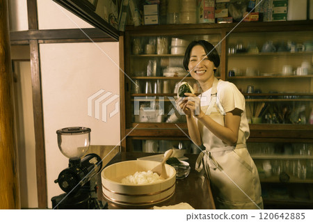 在老民居的廚房裡,一位中年婦女正在綁飯糰。 在老民居的廚房裡,一位中年婦女正在綁飯糰。 120642885