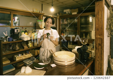 A middle-aged woman tying rice balls in the kitchen of an old-style house A middle-aged woman tying rice balls in the kitchen of an old-style house 120642887