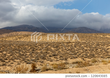 Vast arid landscape in Iran under a cloudy sky with distant mountains 120643085
