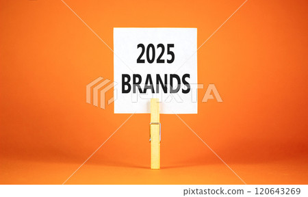 Planning 2025 brands new year symbol. Concept words 2025 Brands on beautiful white paper on wooden clothespin. Beautiful orange background. Business 2025 brands new year concept. Copy space. Planning 2025 brands new year symbol. Concept words 2025 Brands on beautiful white paper on wooden clothespin. Beautiful orange background. Business 2025 brands new year concept. Copy space. 120643269
