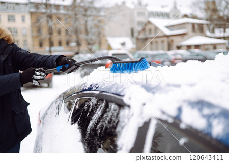 Young man cleaning snow from car with brush. Transport, winter, weather, people and vehicle concept. Young man cleaning snow from car with brush. Transport, winter, weather, people and vehicle concept. 120643411