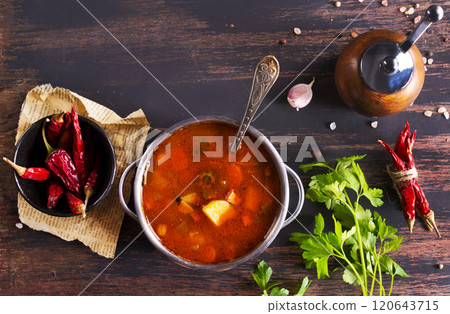 Meat solyanka soup with sausages, olives and vegetables served on wooden table 120643715