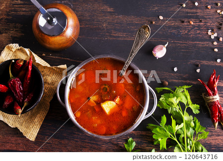 Meat solyanka soup with sausages, olives and vegetables served on wooden table 120643716