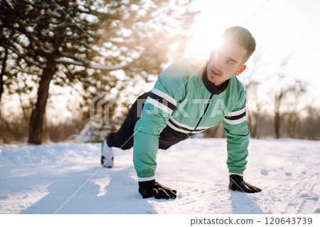 Young sportsman doing workout in forest at snowy winter day. Outdoor fitness, cardio exercises. 120643739