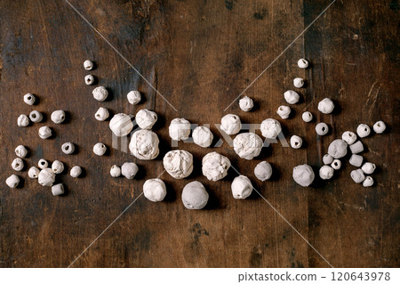 Various shapes unglazed white handmade ceramic beads. Hobby, jewelry assembly, DIY jewelry. Workshop idea. Dark wooden background, top view. Various shapes unglazed white handmade ceramic beads. Hobby, jewelry assembly, DIY jewelry. Workshop idea. Dark wooden background, top view. 120643978