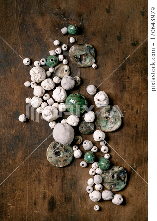 Various shapes and colors handmade ceramic beads, glazed and unglazed. Hobby, jewelry assembly, DIY jewelry. Workshop idea. Dark wooden background, top view. 120643979