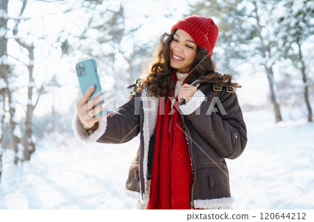 Smiling young woman taking selfie in winter forest. Winter holiday. 120644212