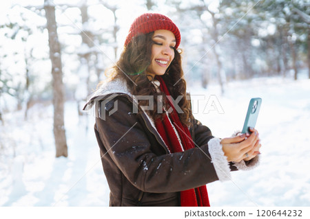 Smiling young woman taking selfie in winter forest. Winter holiday. 120644232