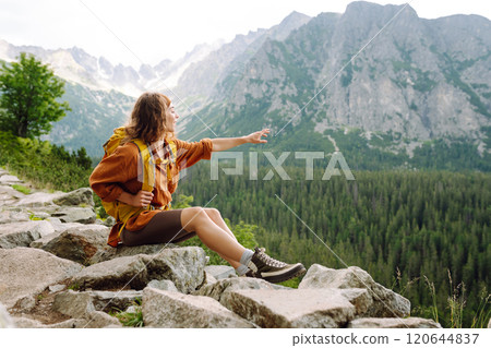 Young traveler woman with a yellow backpack on a cliff. Sports concept, traveler. Active lifestyle. Young traveler woman with a yellow backpack on a cliff. Sports concept, traveler. Active lifestyle. 120644837