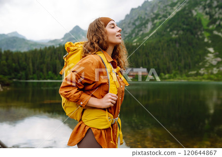 Travel Slovakia, Europe. Tourist with a yellow backpack stands against the backdrop of alpine lake. Travel Slovakia, Europe. Tourist with a yellow backpack stands against the backdrop of alpine lake. 120644867
