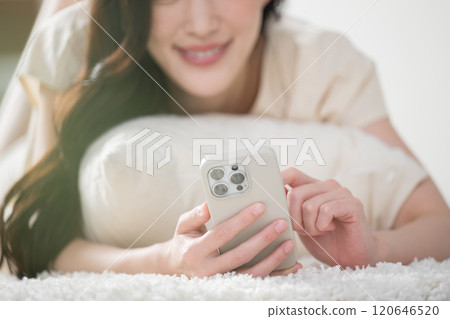 A young woman operating a smartphone in bed or in the living room after waking up, no face 120646520