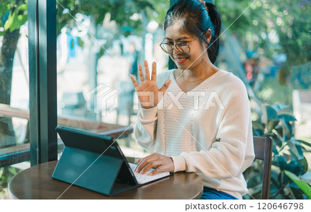 Asian woman is smiling as she has a video call with her friends or family, Sitting at desk, Using laptop computer, Having video chat, education concept, Video conferencing. 120646798