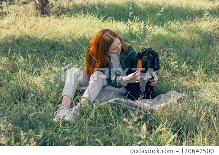 cooling joy of popsicles with pets, summer campaigns more inclusive and fun, red-haired woman, dog in park with ice cream 120647500