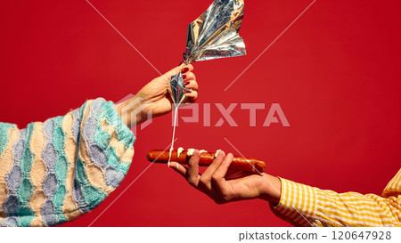 Female hand putting mayonnaise sauce on grilled sausage, Bratwurst against bright red background. Delicious taste of street food 120647928
