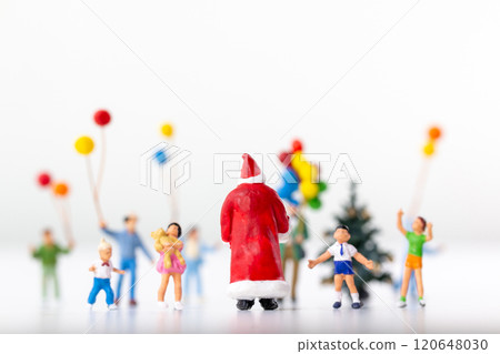 Miniature Santa Claus holding a gift surrounded by children and colorful balloons Miniature Santa Claus holding a gift surrounded by children and colorful balloons 120648030