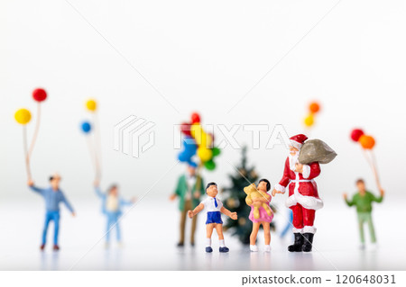 Miniature Santa Claus holding a gift surrounded by children and colorful balloons 120648031