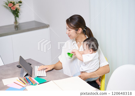 A child playing next to his mother while she is working remotely A child playing next to his mother while she is working remotely 120648318