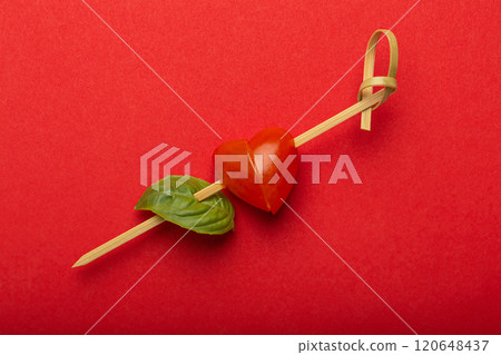 Valentine's Day concept, heart shaped cherry tomato and basil leaf on a skewer for isolated on red background Valentine's Day concept, heart shaped cherry tomato and basil leaf on a skewer for isolated on red background 120648437