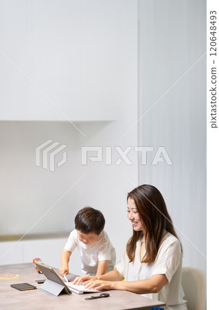 A child playing next to his mother while she is working remotely A child playing next to his mother while she is working remotely 120648493