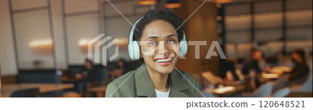 A woman with headphones sitting at a table with coffee and laptop in a nice modern coworking office A woman with headphones sitting at a table with coffee and laptop in a nice modern coworking office 120648521