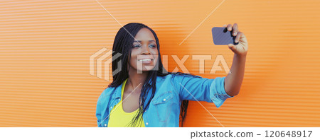 Joyful happy African young woman laughs taking selfie with phone, black girl smiles using smartphone Joyful happy African young woman laughs taking selfie with phone, black girl smiles using smartphone 120648917