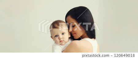 Happy young mother holding cute baby together in white room at home 120649018