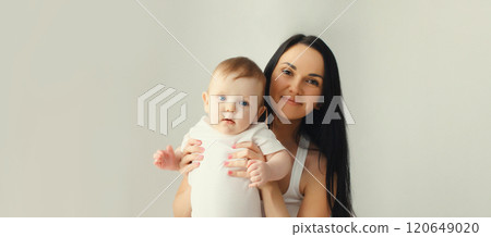 Happy smiling young mother playing with baby in white room at home Happy smiling young mother playing with baby in white room at home 120649020
